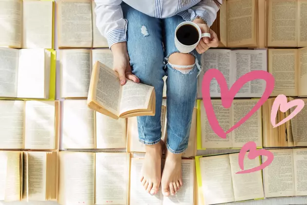 woman sitting on open books, reading a book, drinking coffee